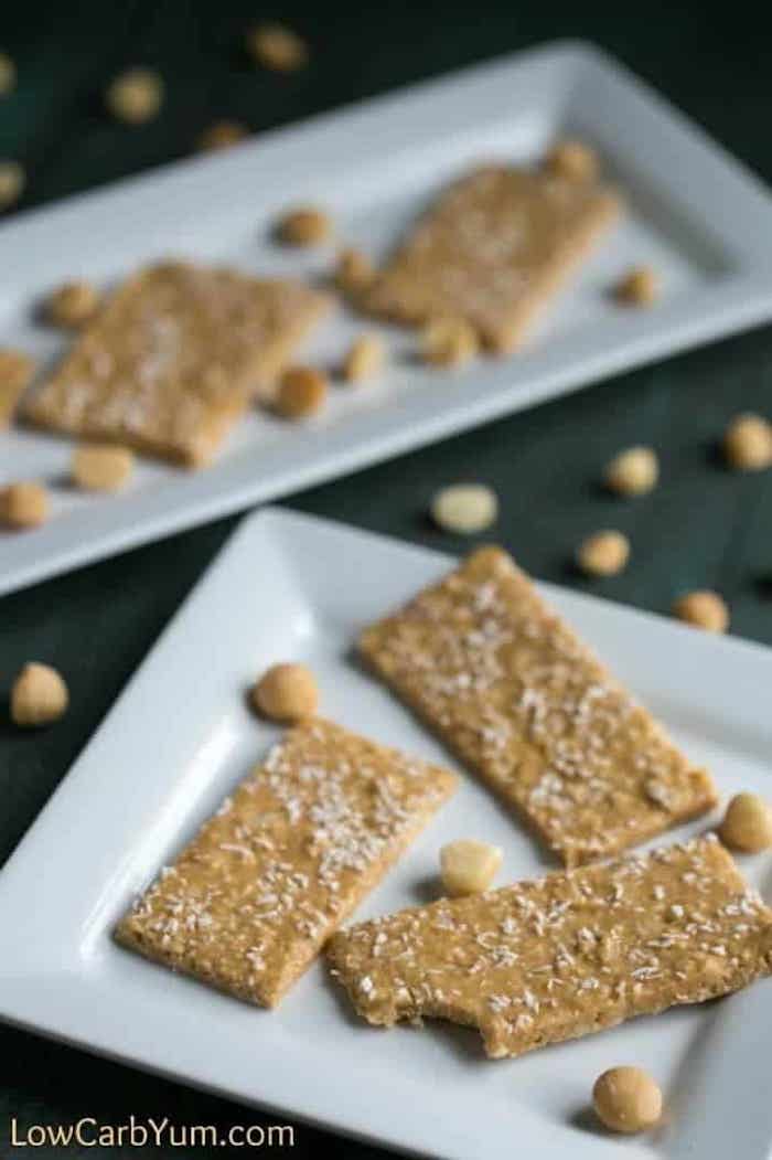 keto breakfast recipes, coconut bars, covered in coconut flakes, with macadamia nuts, on white plates