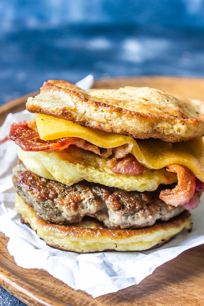 egg sandwich, with bacon and cheese, on white baking paper, high protein low carb breakfast, wooden table