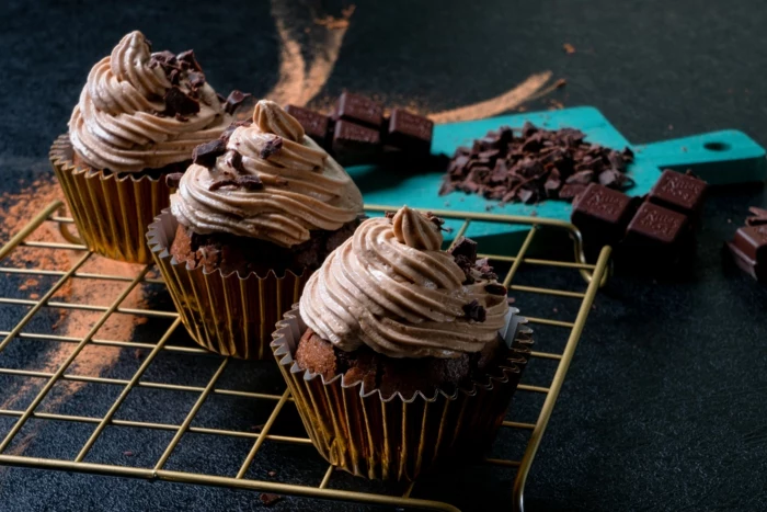 three cupcakes arranged on a rack, chocolate cupcakes recipe, frosting and crumbled chocolate on top