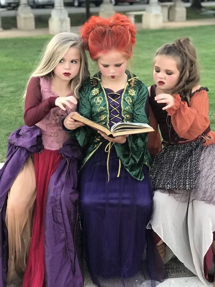 three girl, dressed as witches, hocus pocus movie inspired, twin halloween costumes, long gowns, reading a book