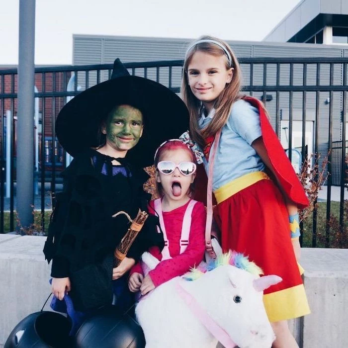 twin halloween costumes, three girls, dressed as a witch, unicorn and supergirl
