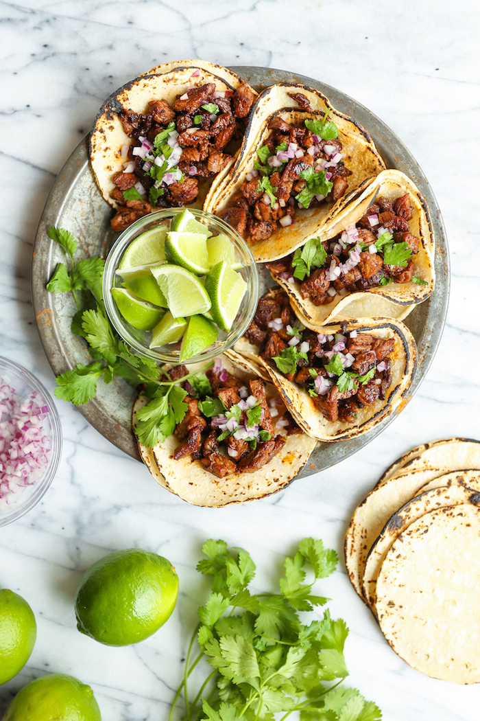 five tacos, tortilla wraps, filled with beef, how to make taco meat, arranged on a silver plate, lime slices, in a glass bowl