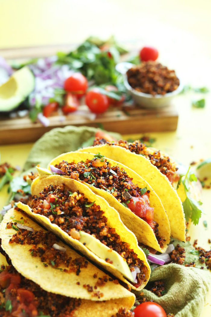 tortilla wraps, filled with salsa, boiled quinoa, taco ingredients, green table cloth, wooden cutting board