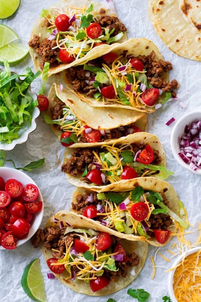 six tacos, how to make taco meat, tortilla wraps, filled with beef, cherry tomatoes, cheese on top, lime slices