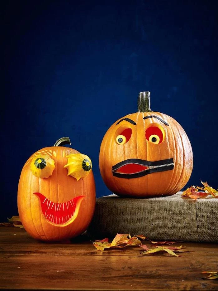 two pumpkins, arranged on a wooden table, with fall leaves, easy pumpkin carving ideas, blue background