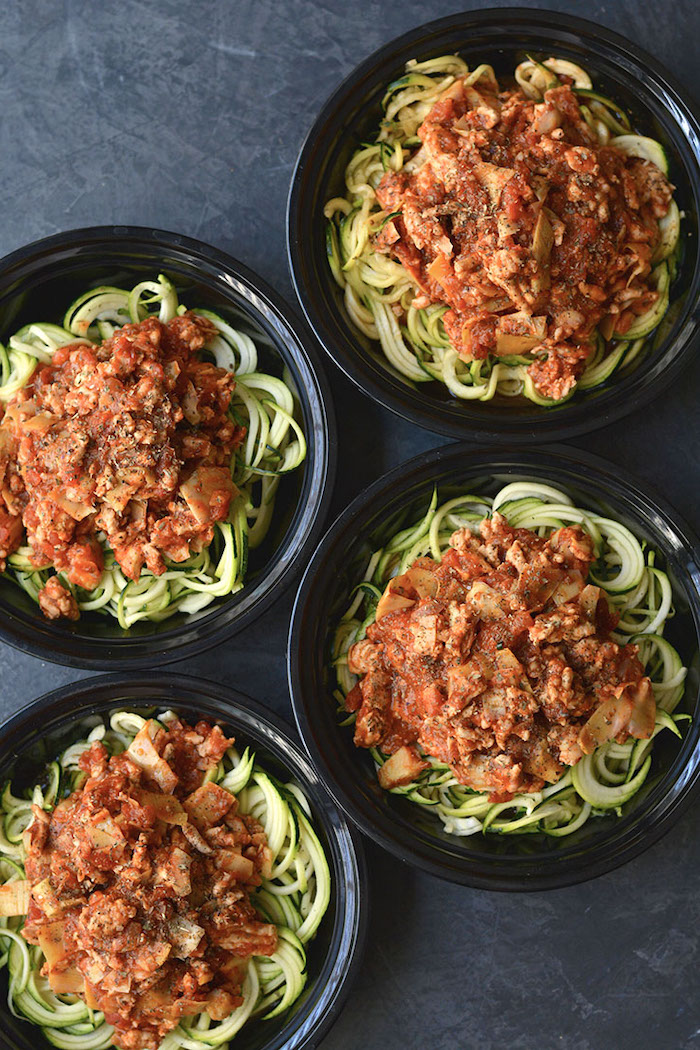 four black plastic, round containers, what are zoodles, bolognese zucchini noodles, meal prep ideas
