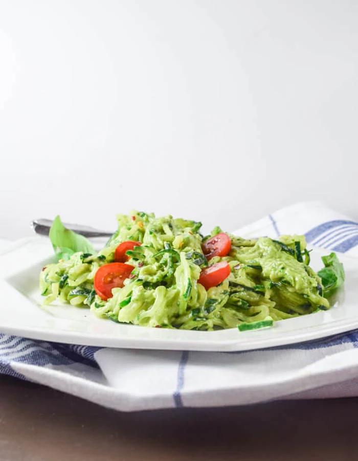 white and blue table cloth, white plate, how to cook zucchini noodles, zoodles with pesto, cherry tomatoes