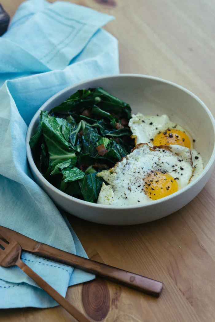 fried eggs, spinach and bacon, on the side, easy keto meals, white bowl, blue table cloth, wooden table