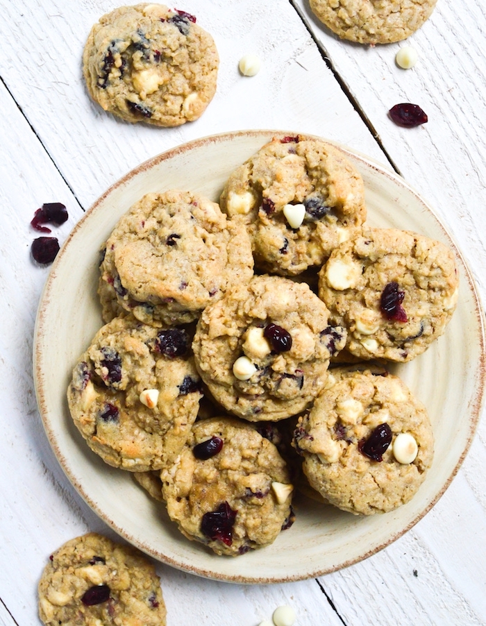 homemade chocolate chip cookies, with raisins, white chocolate chips, in a white plate, white wooden table