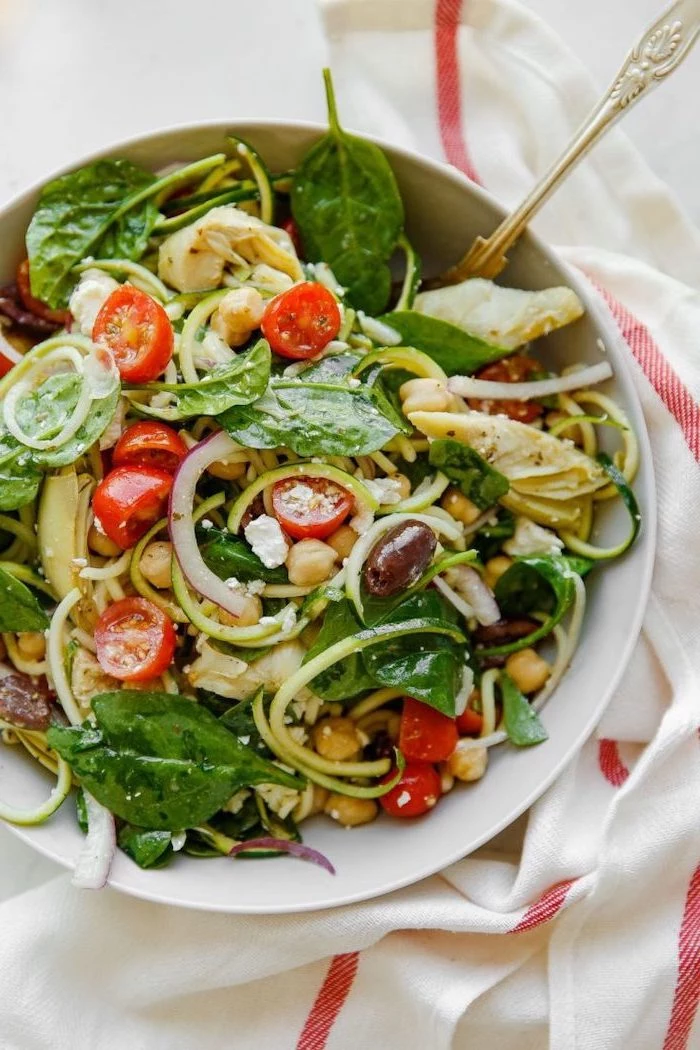 basil leaves, cherry tomatoes, what are zoodles, zucchini noodles, in a white bowl, white cloth