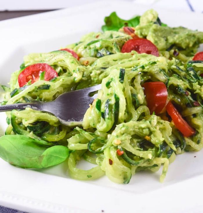 cherry tomatoes, zoodles with pesto, how to cook zucchini noodles, white plate, silver fork, basil leaves