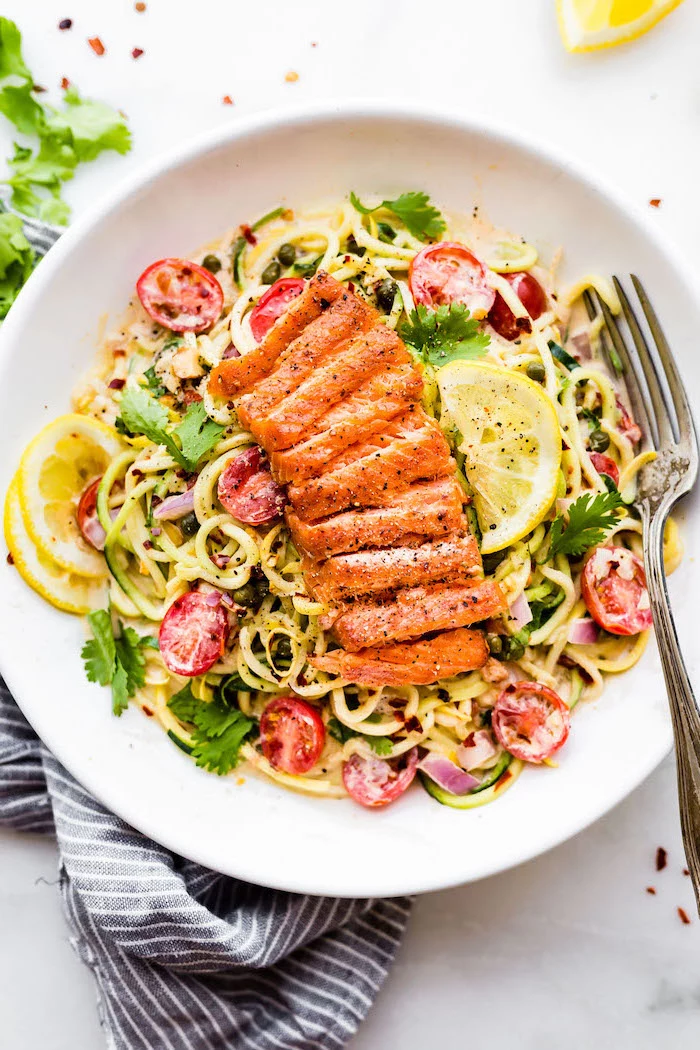 salmon on top, zoodles with sauce, cherry tomatoes, making zucchini noodles, white plate, silver fork