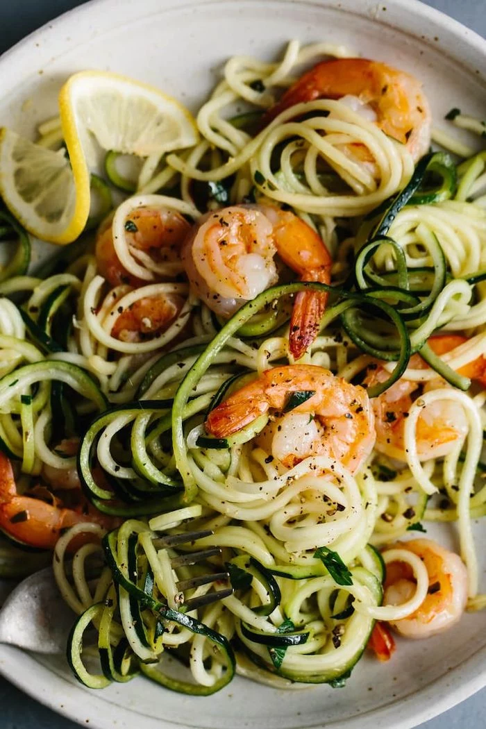 shrimp zoodles, in a white plate, lemon slice on the side, zucchini noodles spaghetti