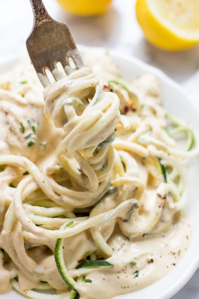 white plate, how to cook zucchini noodles, lemon cream sauce, lemon slices, on the side