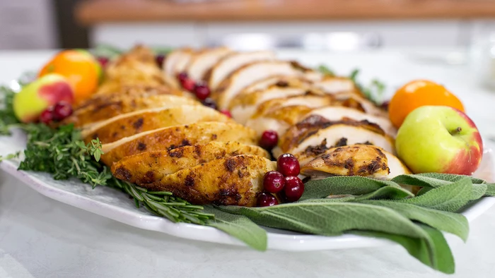 turkey slices, fresh herbs, apples and tangerines, cranberries on the side, how to bake a turkey, white plate