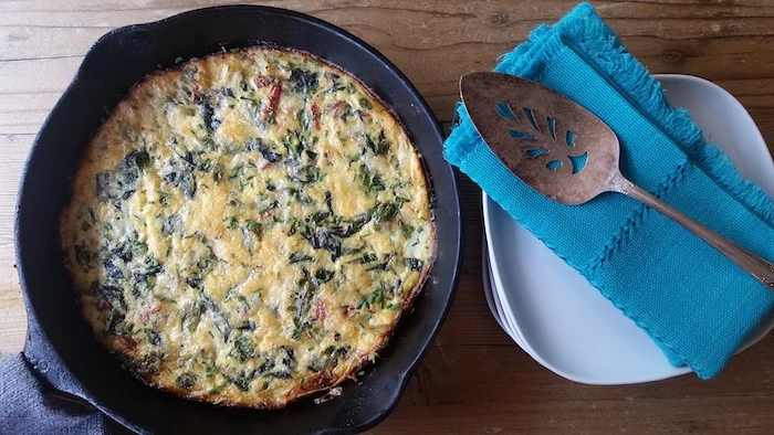 baked frittata, in black skillet, weeknight dinners, white plates, blue cloth, wooden table, metal spatula
