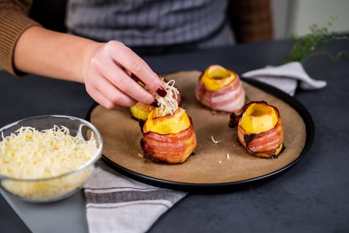 baked potato volcanoes, wrapped with bacon slices, filled with cheese, baked potato volcanoes, placed on paper lined baking sheet
