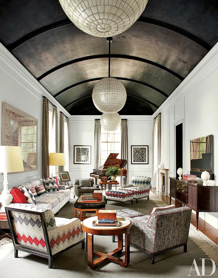 vaulted ceiling, barrel ceiling, colorful printed armchairs, wooden floor, large grey carpet, white walls