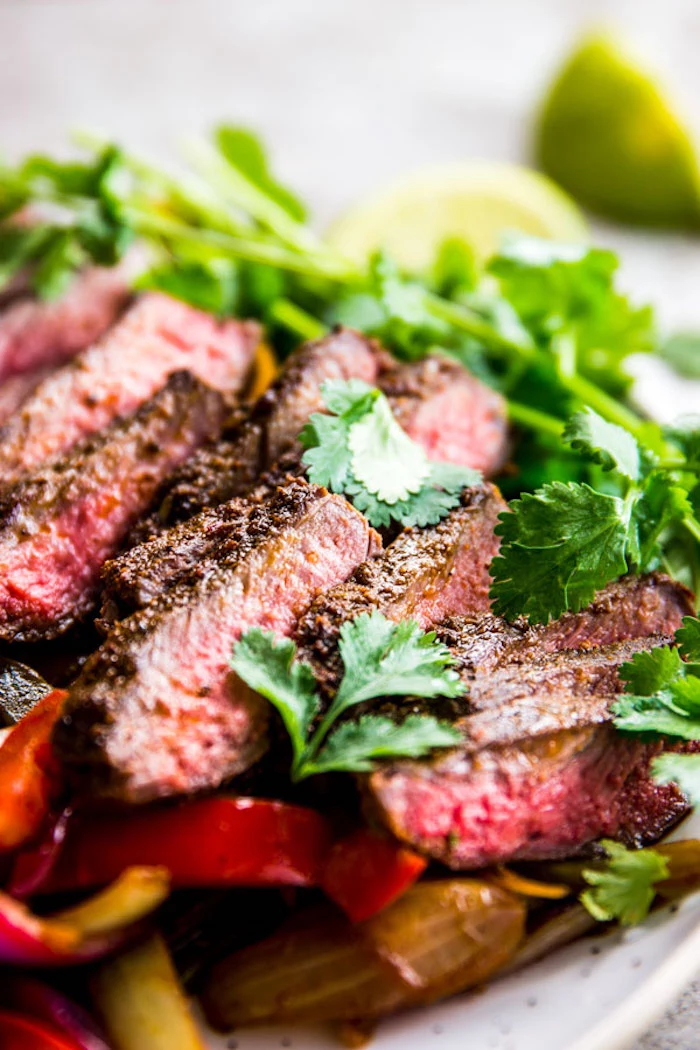 steak fajitas, sliced peppers, parsley garnish, low calorie meals, white plate, blurred background