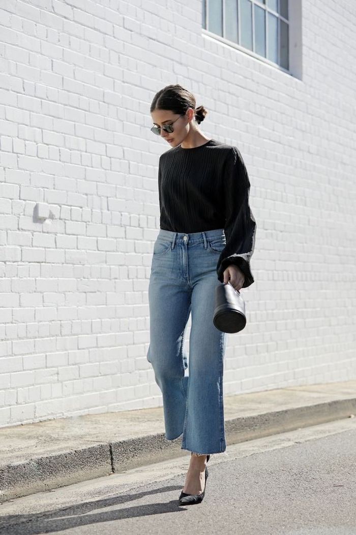 woman walking down the street, wearing black blouse and jeans, medium length hairstyles for women, carrying black bag