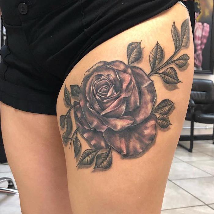 large rose, flower thigh tattoo, black shorts, white tiled floor, black leather chair, in the background