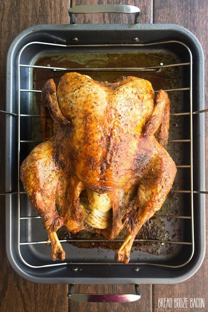 roasted turkey, on a railing, on black pan, thanksgiving turkey recipe, wooden table