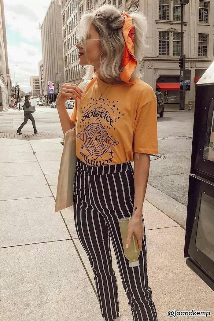 woman with blonde hair, half up tied with silk scarf, wearing orange t shirt, black and white striped pants, medium haircuts for women