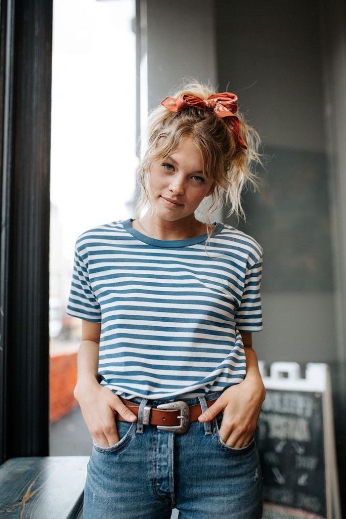 woman with curly blonde hair in a ponytail, tied with a bandana, medium haircuts for women, wearing blue and white t shirt and jeans