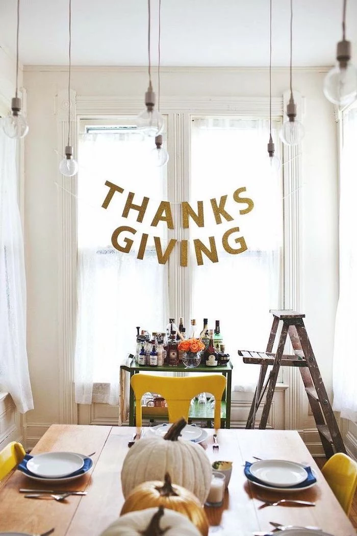 thanksgiving banner, turkey decoration, pumpkins arranged on table, plate settings, alcohol bar, wooden ladder