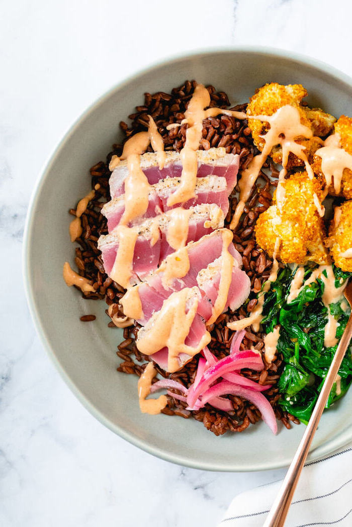 easy dinner recipes for two, tuna slices, brown rice, with spinach, in a white bowl, marble countertop