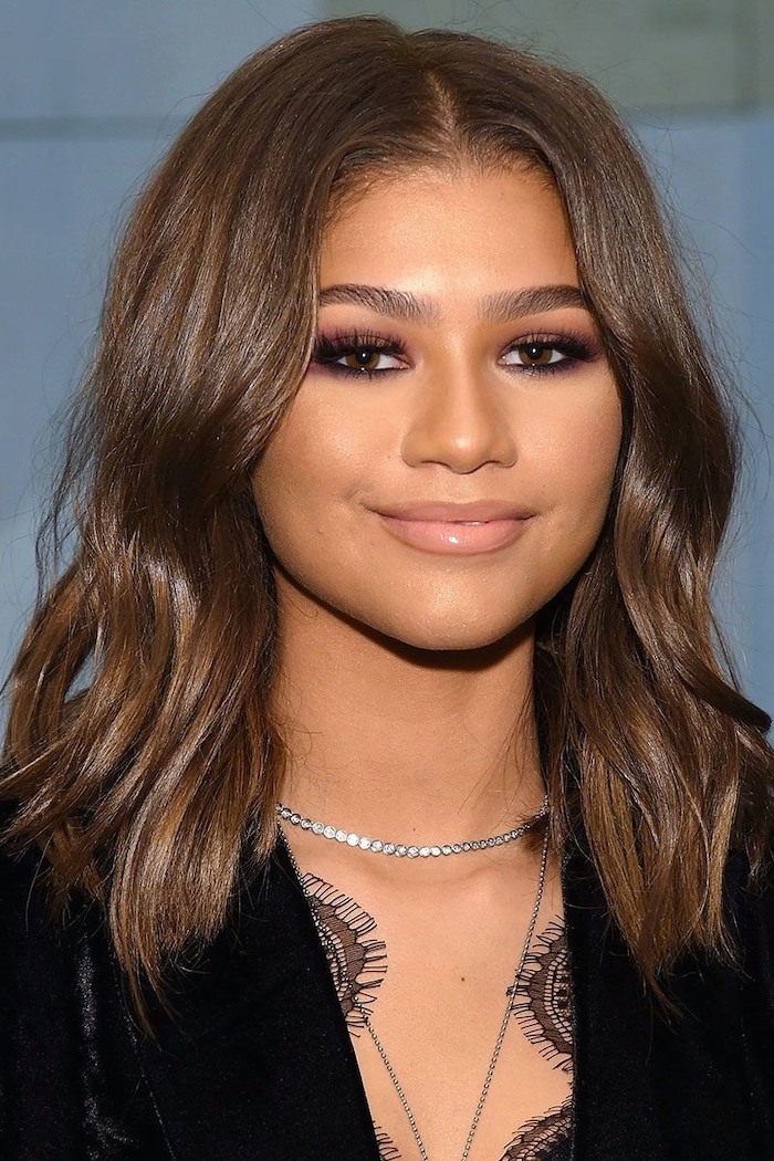 medium length hairstyles, zendaya smiling at the camera, brown wavy hair, wearing black velvet dress, silver necklace