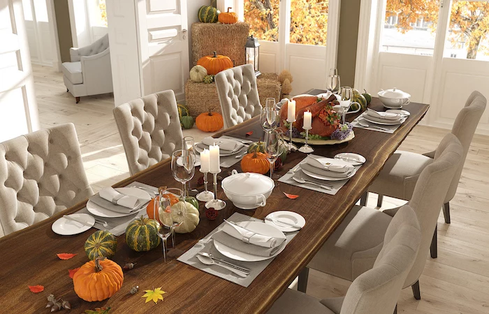 wooden table, white chairs, fall decor, pumpkins scattered around, wine glasses, candles and leaves