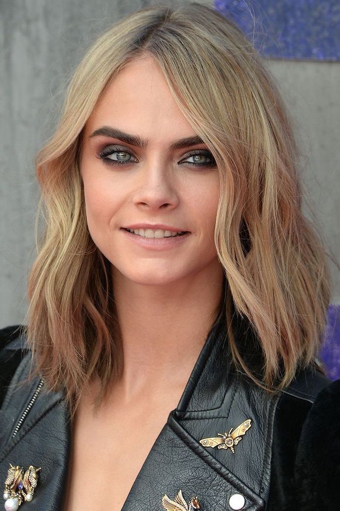 cara delevingne smiling, wearing black leather jacket, with blonde wavy hair, medium length hairstyles