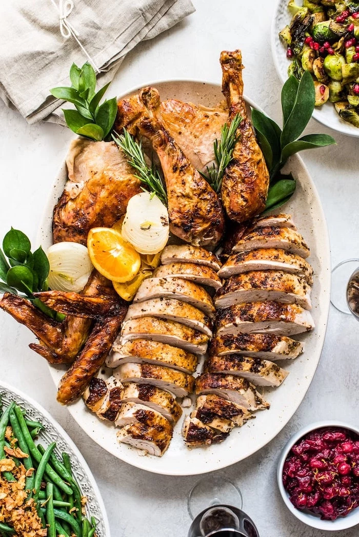 how long to bake a turkey, carved turkey, lemon slices, fresh herbs, on the side, white table, white plate