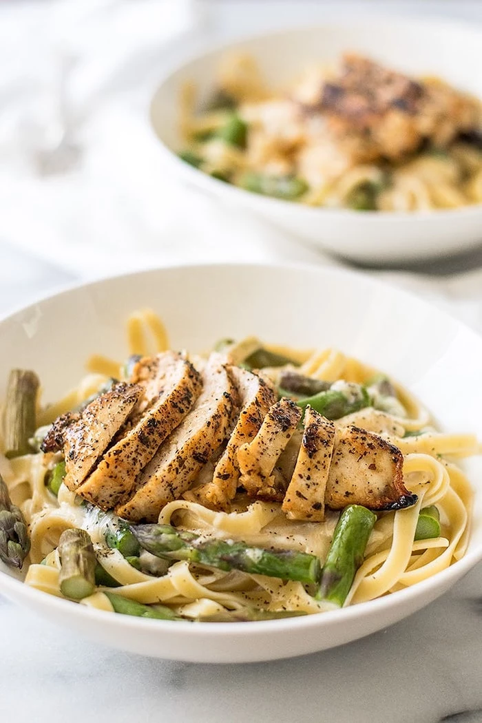 chicken breast, on top of pasta with asparagus, in white bowl, easy dinner recipes for two, marble countertop