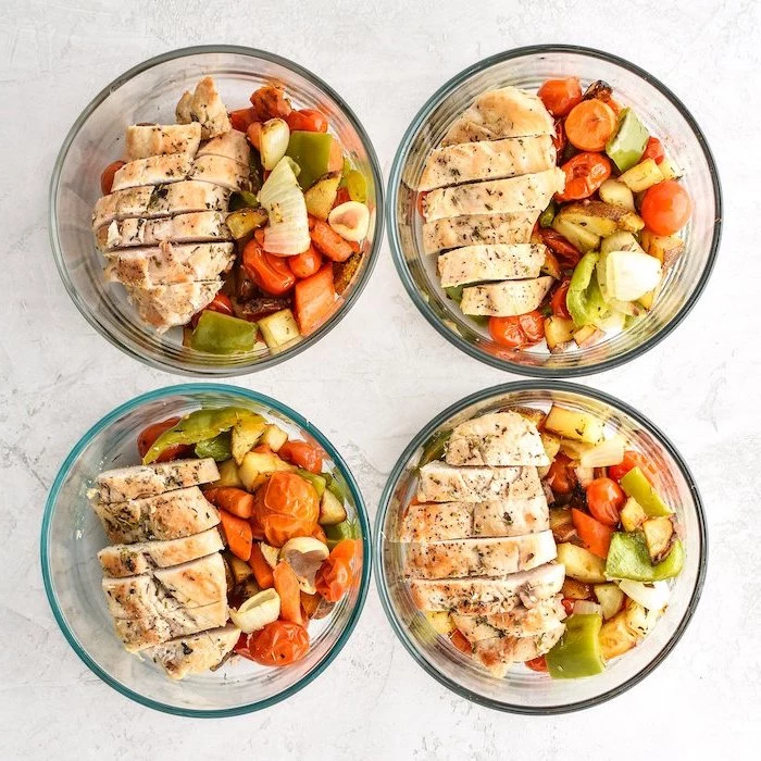 four glass containers, baked veggies, sliced chicken breasts inside, meal prep for weight loss, white table
