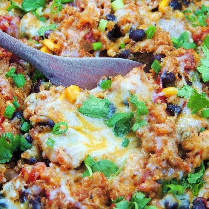 easy weeknight dinners, chicken enchilada, with quinoa, black beans, corn and tomatoes, stirred with wooden spatula