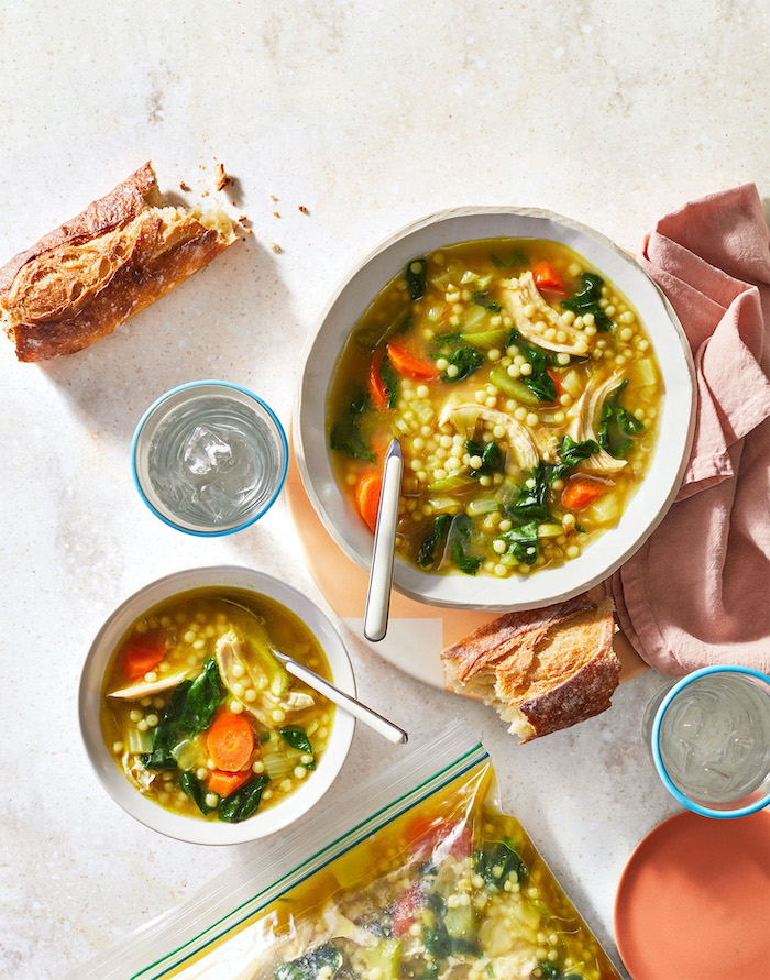chicken soup, with couscous and carrots, in white bowls, baguette cut in half, on the table, easy healthy dinner ideas