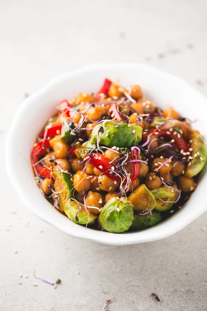 chickpea and vegetables stir fry, with sesame seeds, in white ceramic bowl, healthy dinner ideas, white table