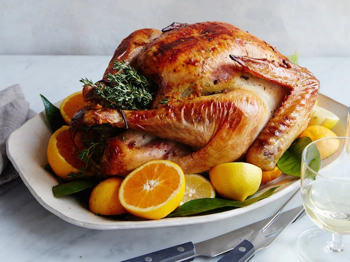 white plate, how long to bake a turkey, roasted turkey, fresh herbs, lemon slices, on the side, wine glass