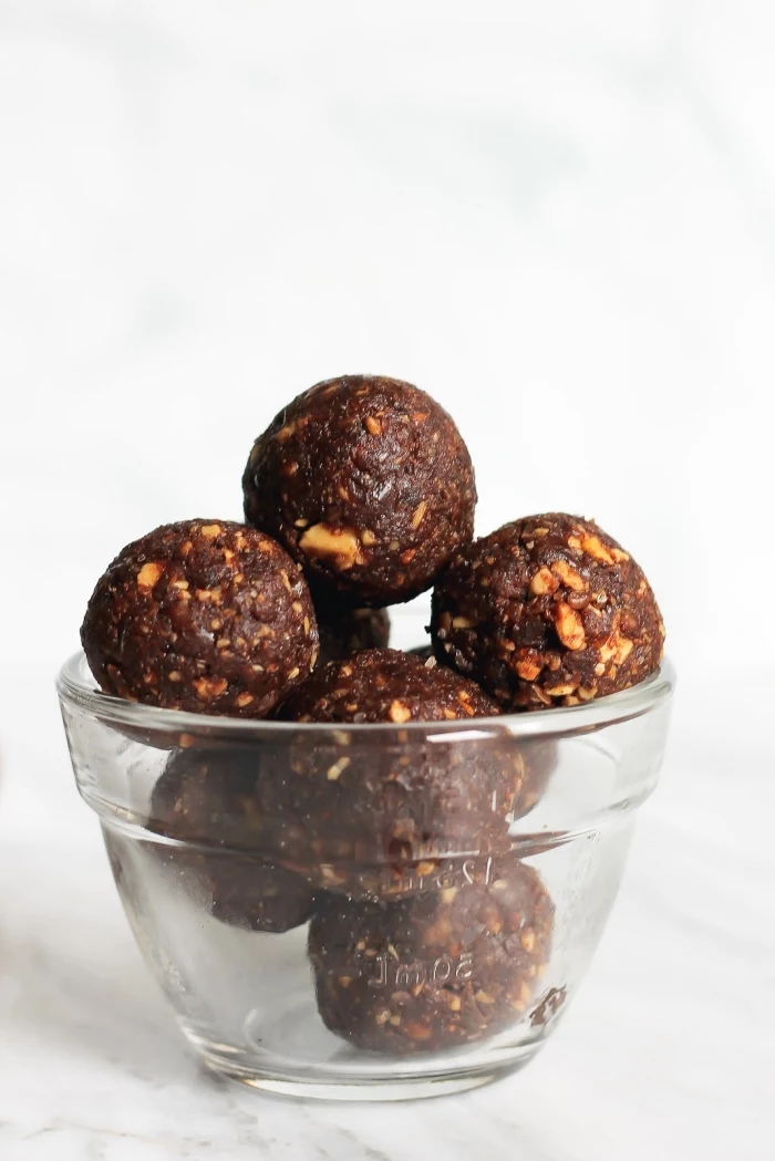 white background, peanut butter energy balls, chocolate truffles, with nuts, in a glass bowl