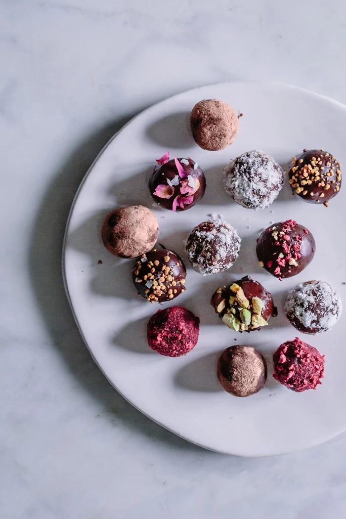 marble countertop, no bake protein balls, covered with cocoa, coconut flakes, pistachio nuts