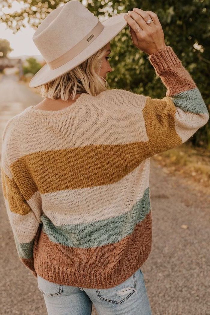 woman wearing a hat, colorful sweater and jeans, shoulder length layered hair, blonde wavy hair