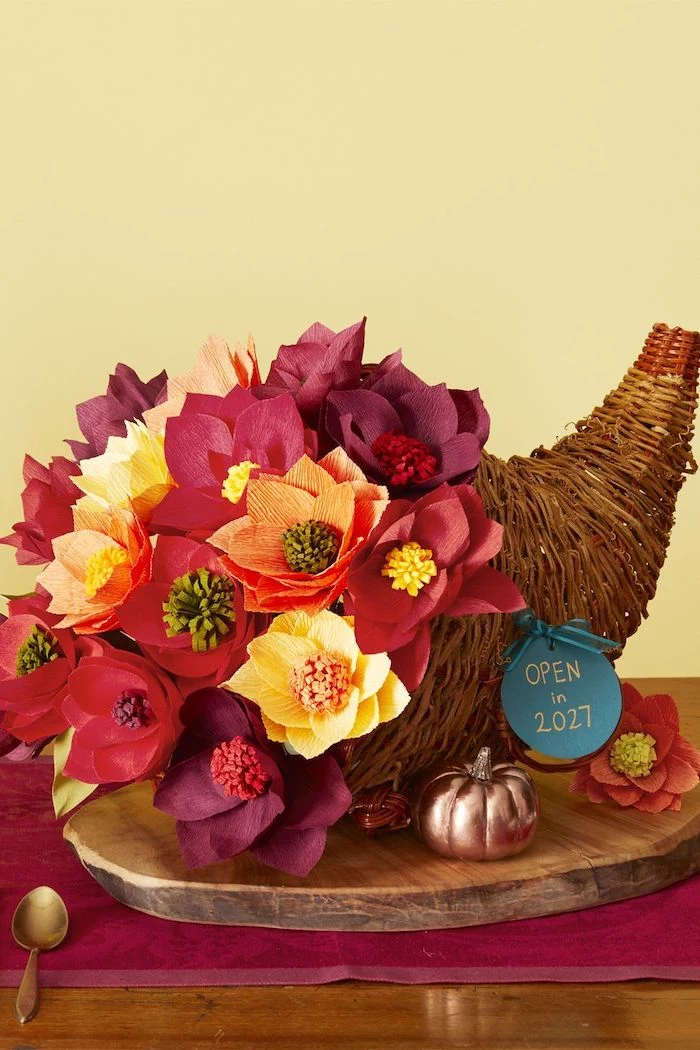 cornucopia with faux, paper flowers, thanksgiving decorating ideas, wooden log, red table runner