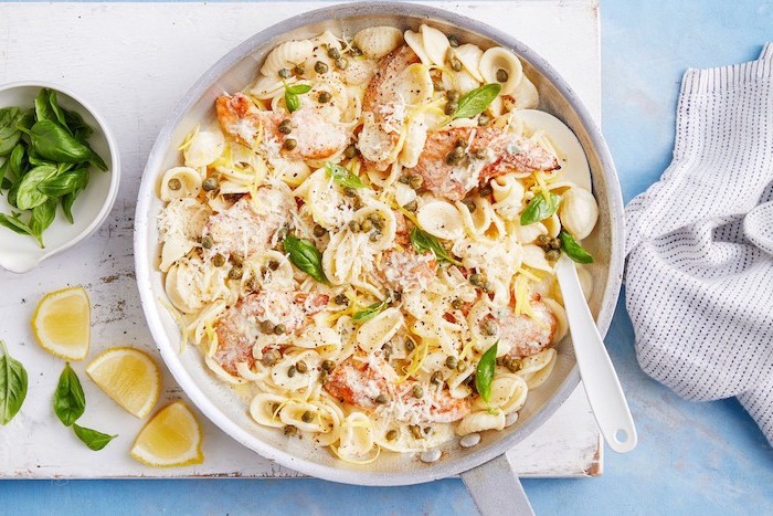easy healthy dinner ideas, creamy chicken pasta, basil leaves for garnish, white wooden board, lemon slices