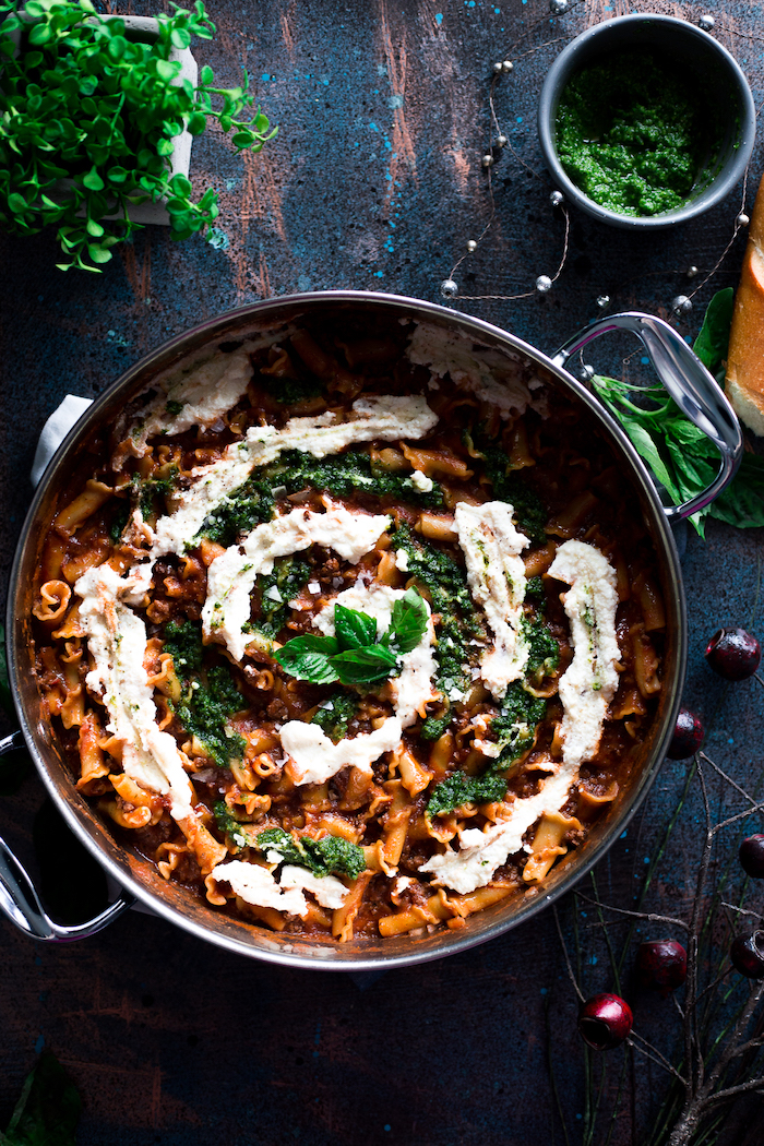 creamy pesto lasagna, sauce on top, basil leaves for garnish, in a pot, easy healthy dinner ideas, black table