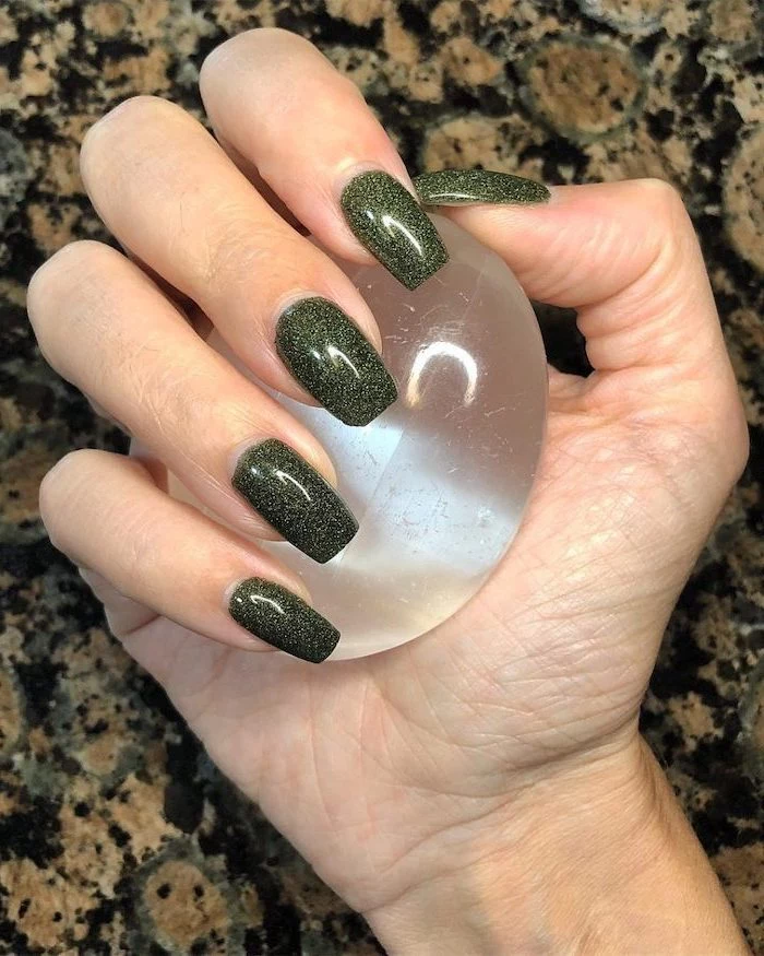 green glitter, nail polish, fall nail designs, hand holding a crystal ball, long square nails, granite countertop