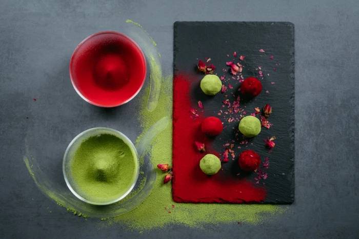 energy balls, cocoa in glass bowls, dyed in red and green, black cutting board, chocolate truffles