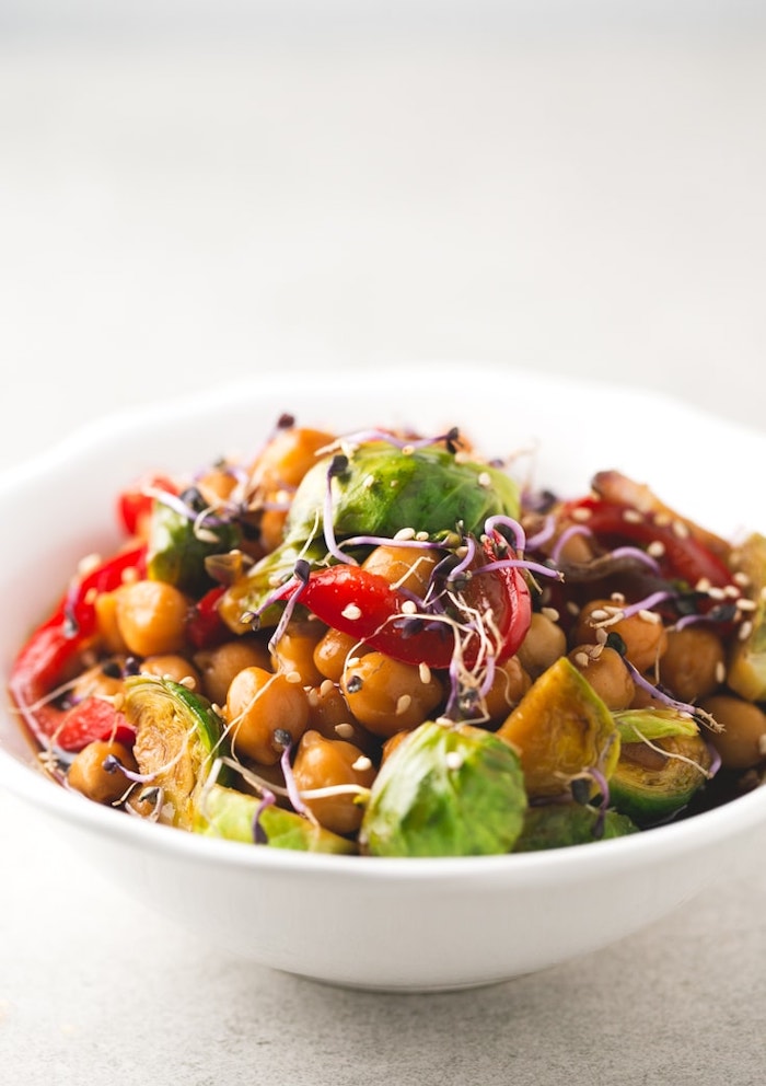 white ceramic bowl, healthy dinner ideas, chickpea and vegetables stir fry, with sesame seeds, white table