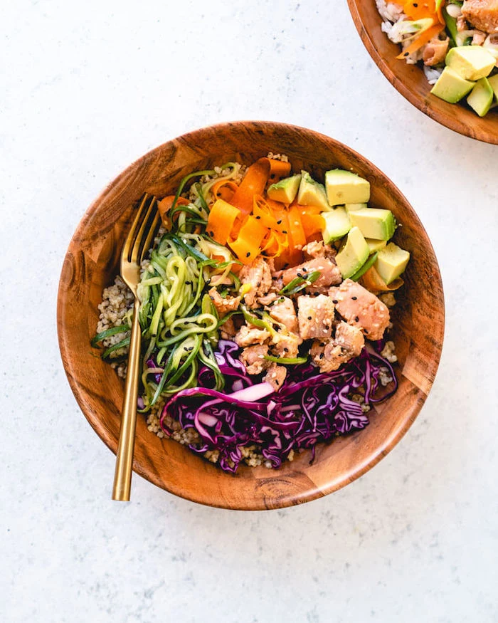 seared salmon, zucchini and carrots noodles, quinoa and avocado, in a wooden bowl, dinner ideas for tonight, white table